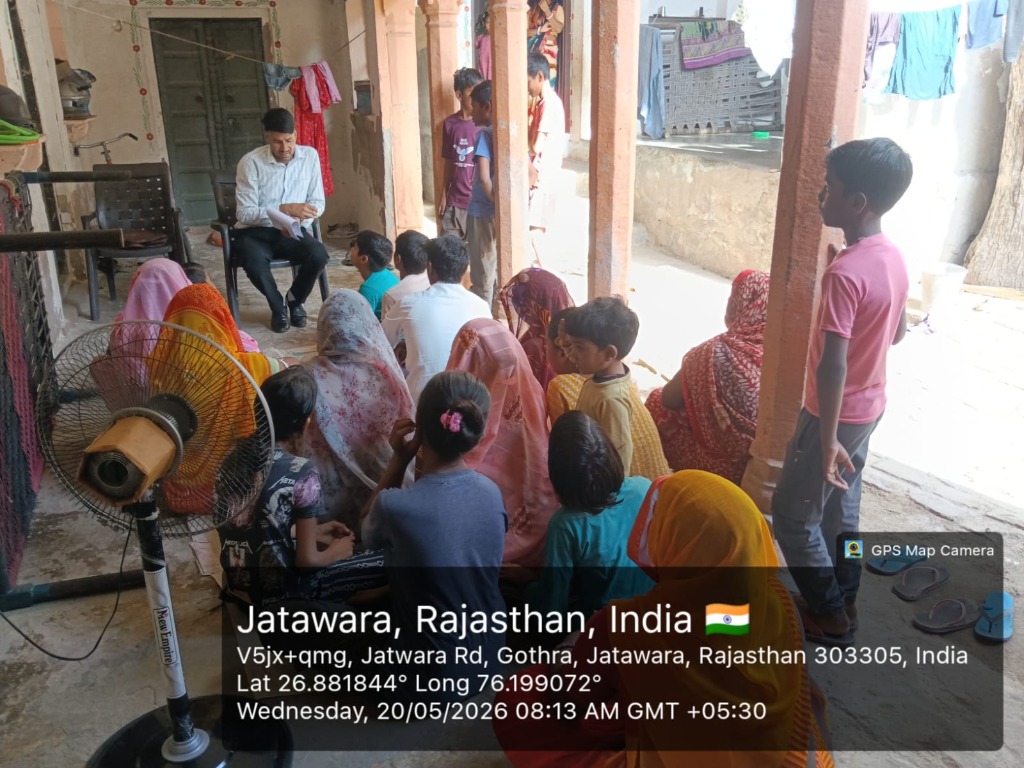 Parents and children sitting in village courtyard for a local meeting in Jatawara, Rajasthan